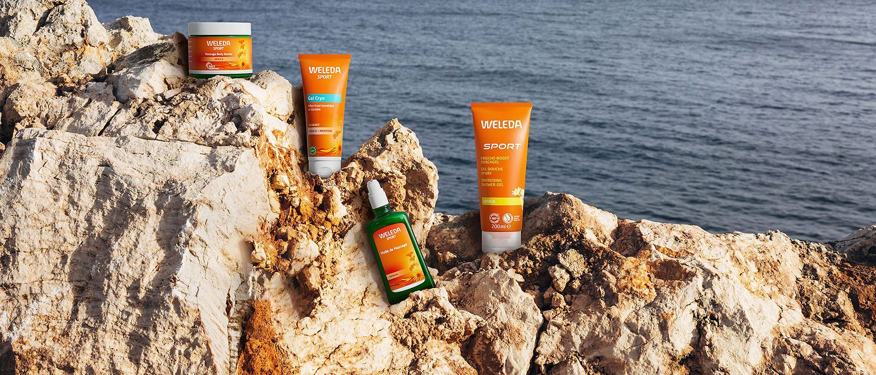 Weleda Arnika Produkte auf einem Felsen am Meer