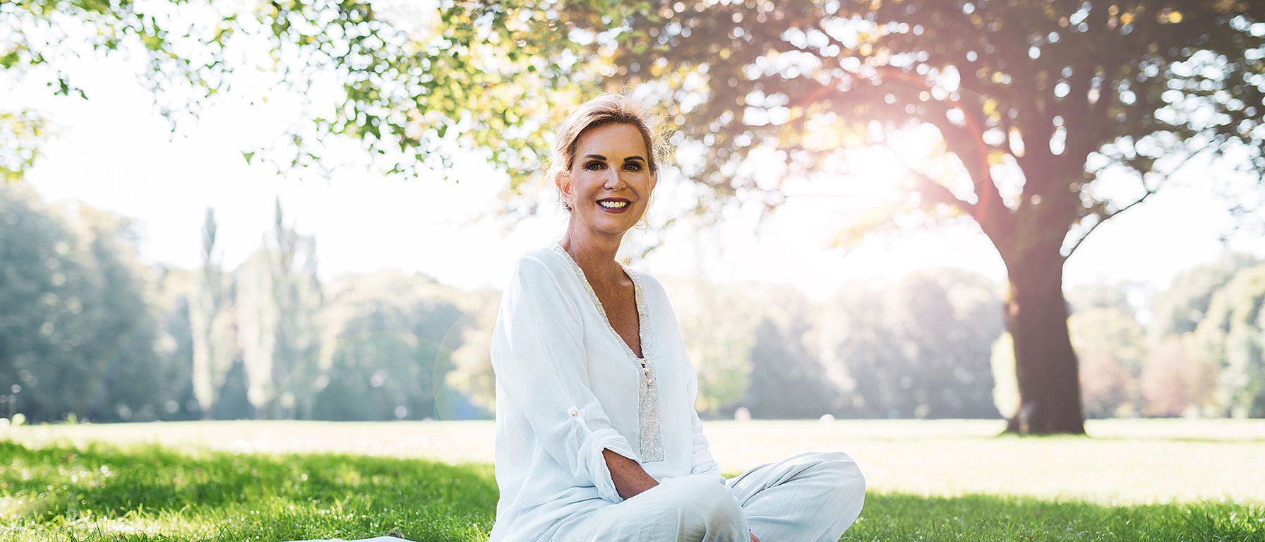 Une femme âgée est assise dans le parc sur une couverture