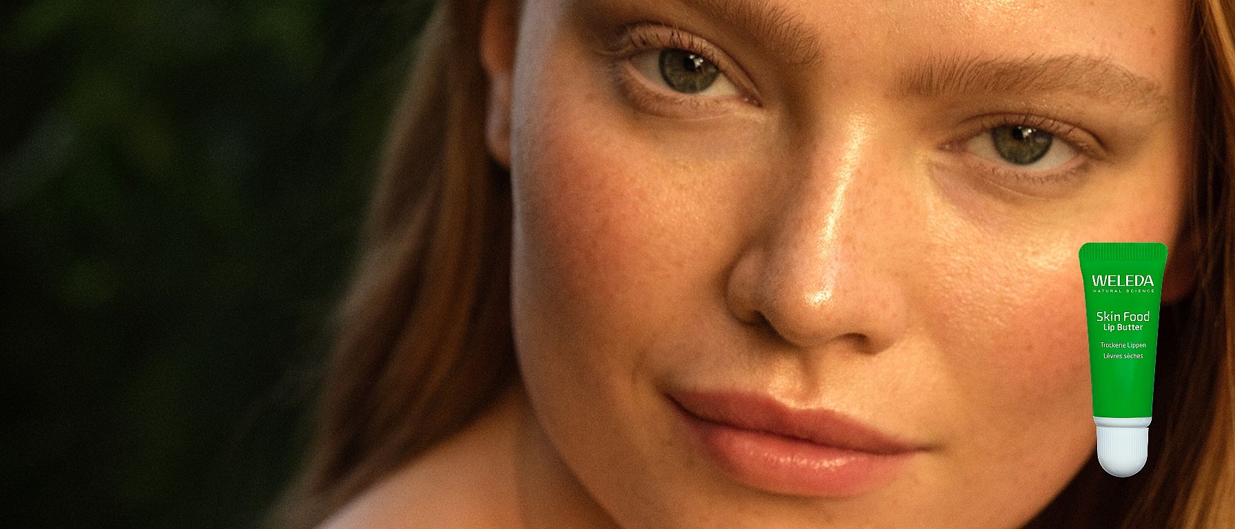 Frontale Ansicht einer Frau mit neutralem Gesichtsausdruck. Außerdem Abbildung des neuen Weleda Skin Food Lip Balm