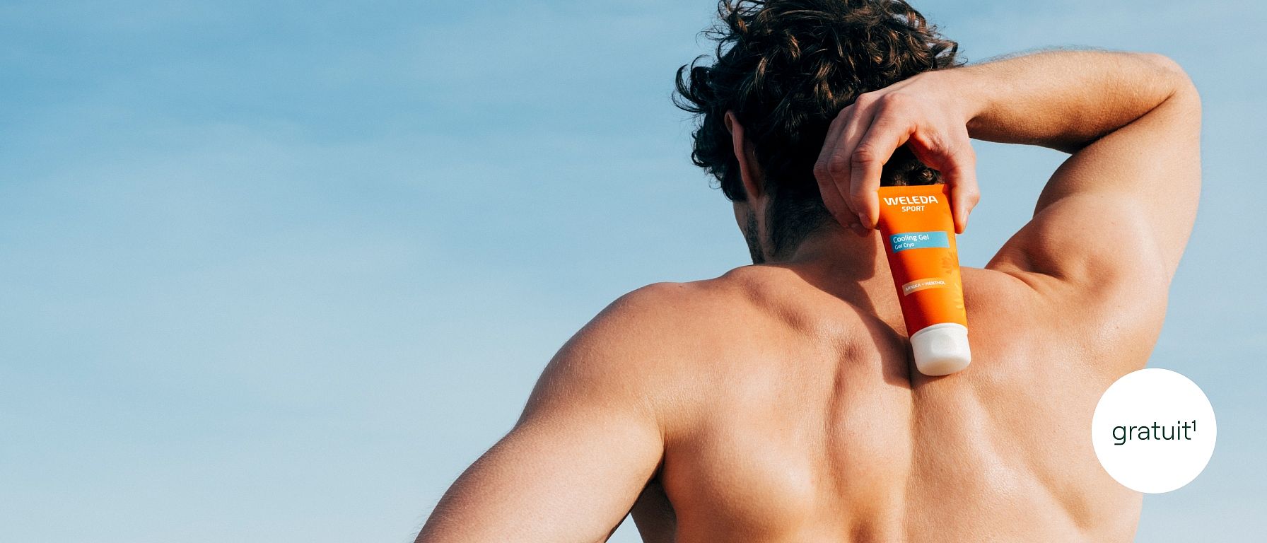 L'homme tient le gel réfrigérant à l'arnica Weleda contre son dos