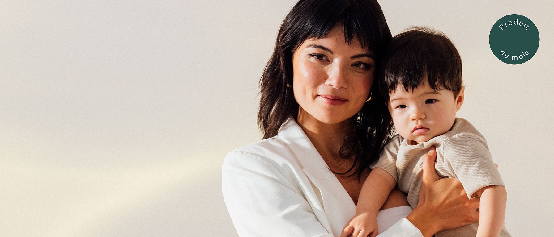 Une femme en blazer blanc tient un petit enfant dans ses bras