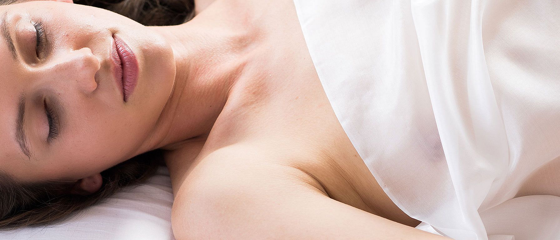 Junge Frau liegt mit geschlossenen Augen im Bett