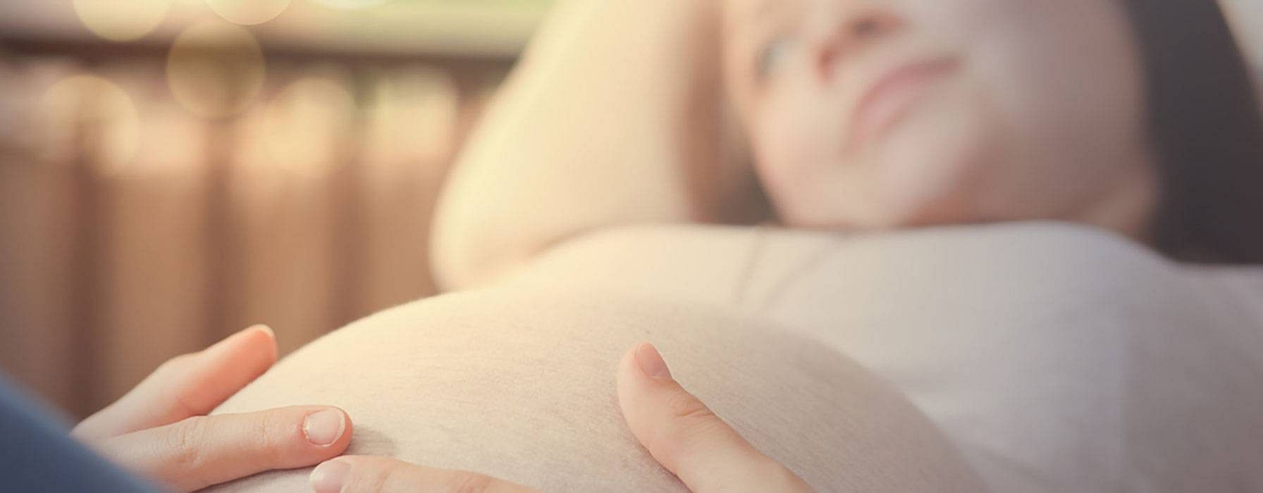 Schwangere Frau liegt auf dem Bett