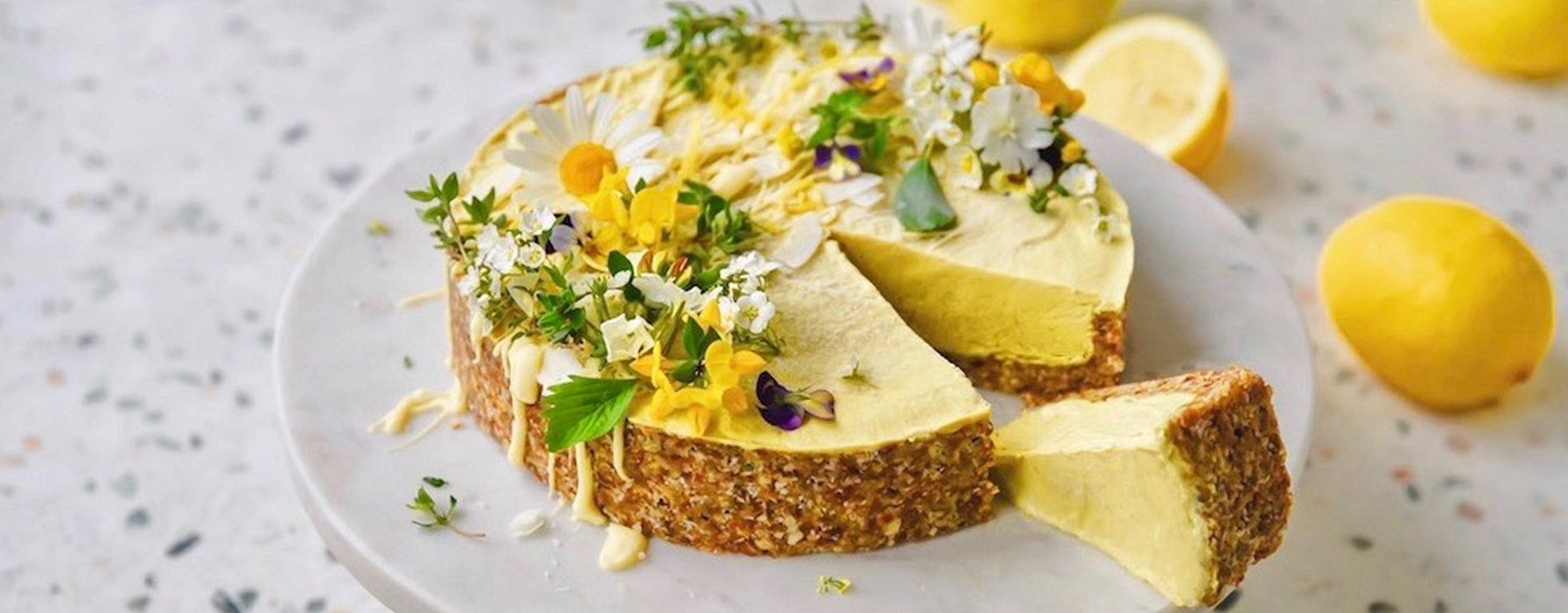 Zitronenkuchen mit Blüten und Zitronen auf einer Platte