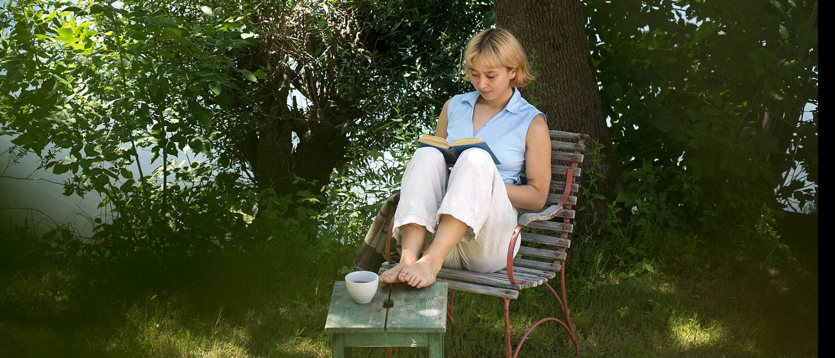 Frau liest im Schatten