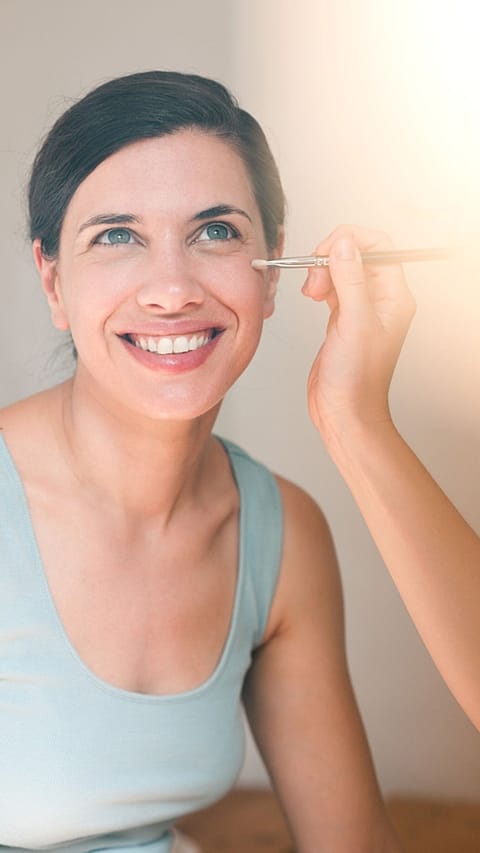 Jeune femme souriante se fait maquiller