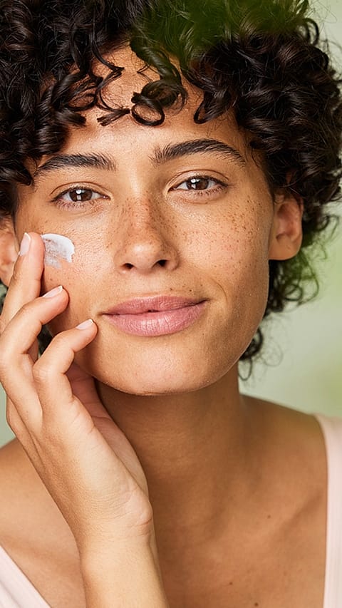 Jeune femme applique une creme de visage