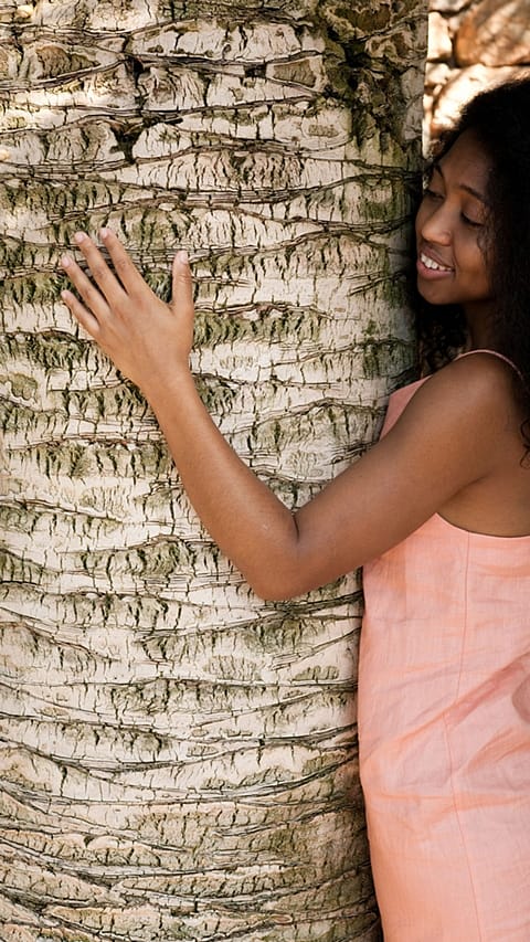 Jeune femme touche le tronc d'un arbre
