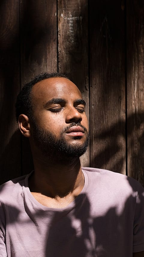 L'homme est assis les yeux fermés au soleil