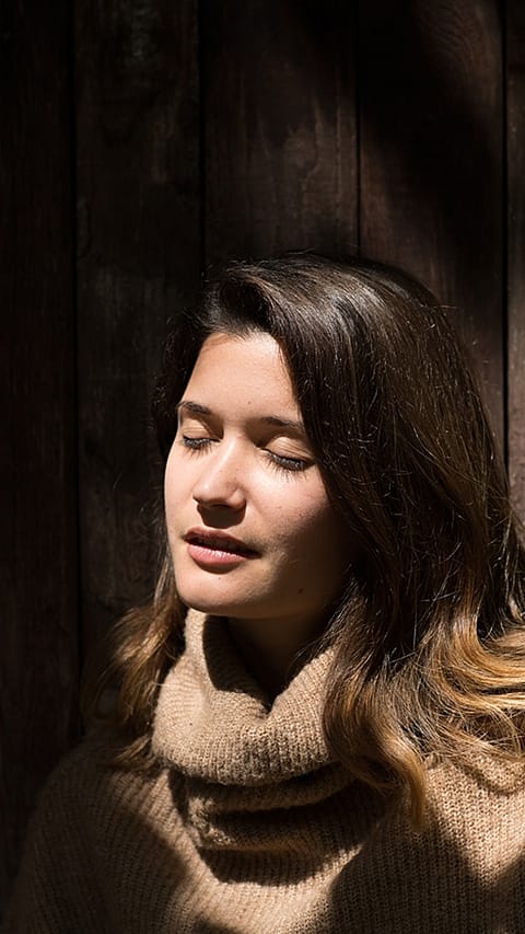 La femme est assise les yeux fermés au soleil