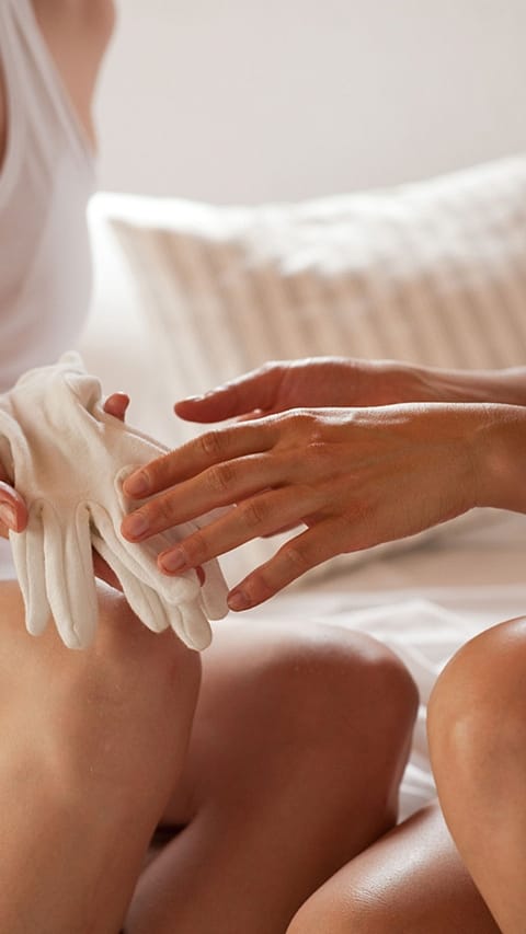 Femme met des gants de soin après massage des mains