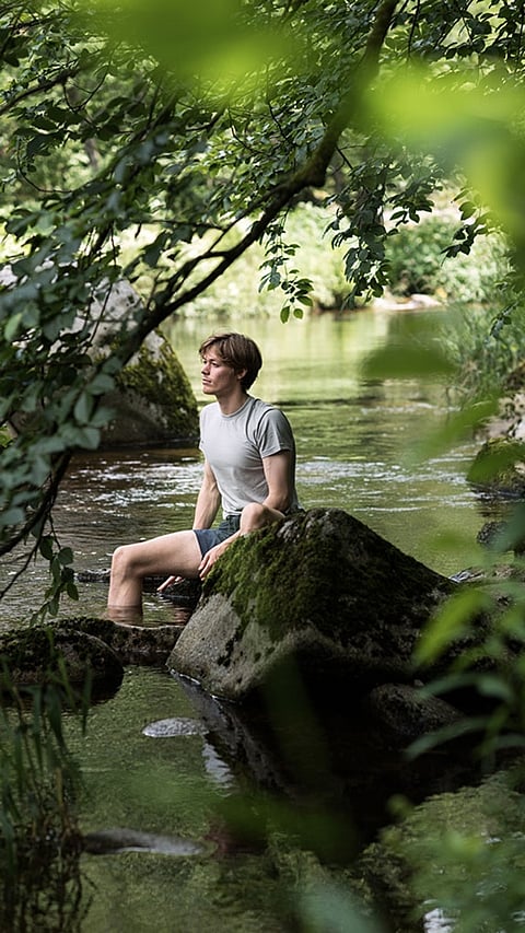 Homme au bord de la rivière entouré de forêt