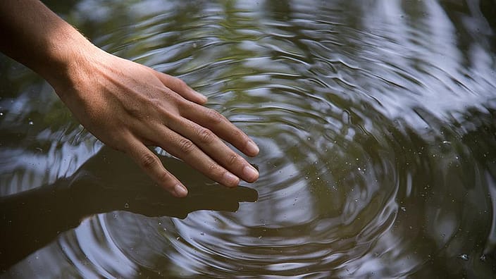 Ein Hand streicht über das Wasser