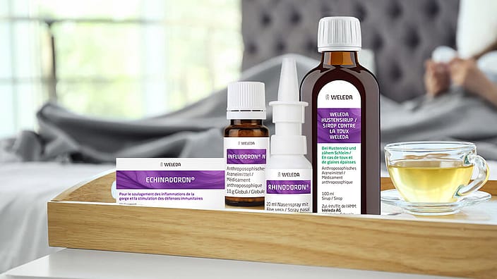 Sirop contre la toux, Infludoron, Echinadoron, Rhinodoron et thermomètre sur la table, enfant endormi en arrière-plan