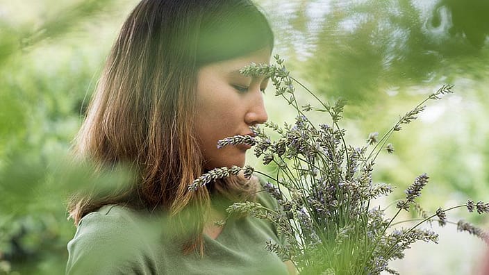 Femme dans la nature sentant un arbuste avec de la lavande