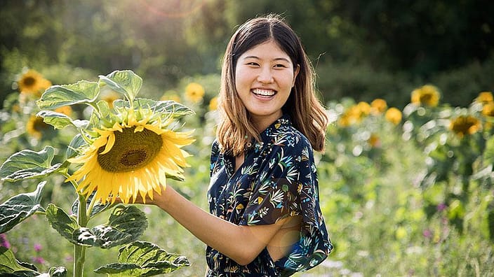 Femme avec un tournesol dans un champ de tournesols