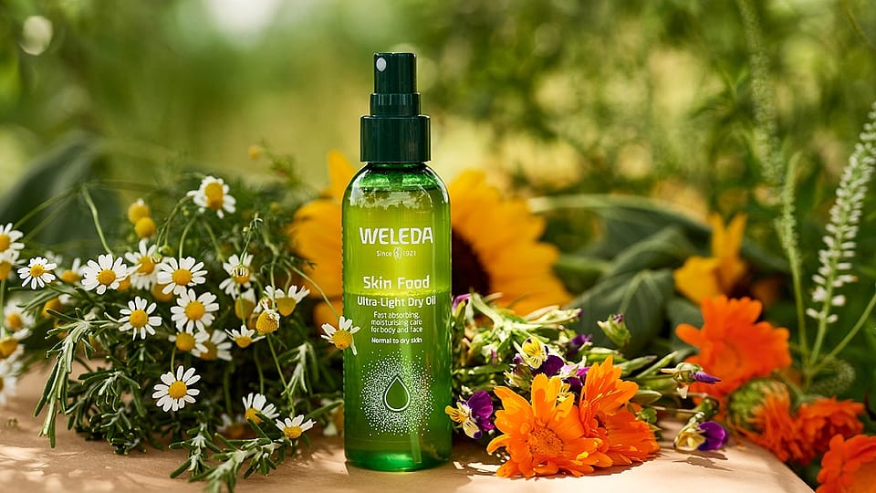 Skin Food Ultra-Light Dry Oil entourée de fleurs