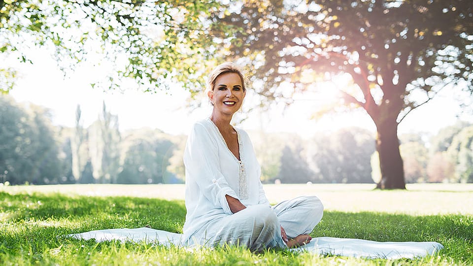 Une femme âgée est assise dans le parc sur une couverture