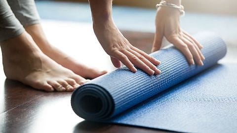 Une femme enroule un tapis de yoga