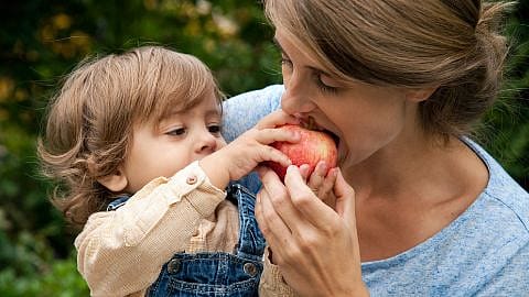 Le fils donne à sa maman une pomme à croquer
