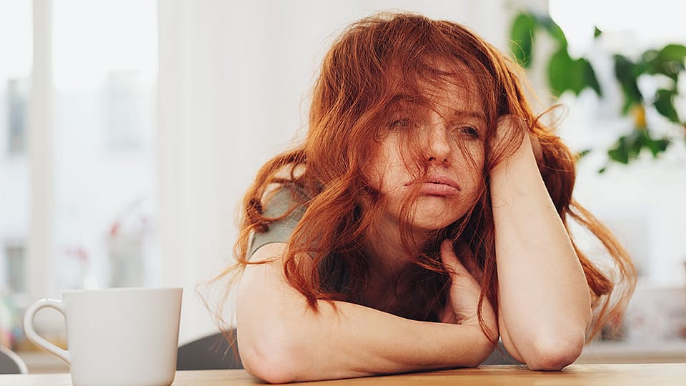 Une femme assise fatiguée à côté d'une tasse de café