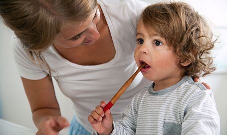 Une mère brosse les dents de son enfant