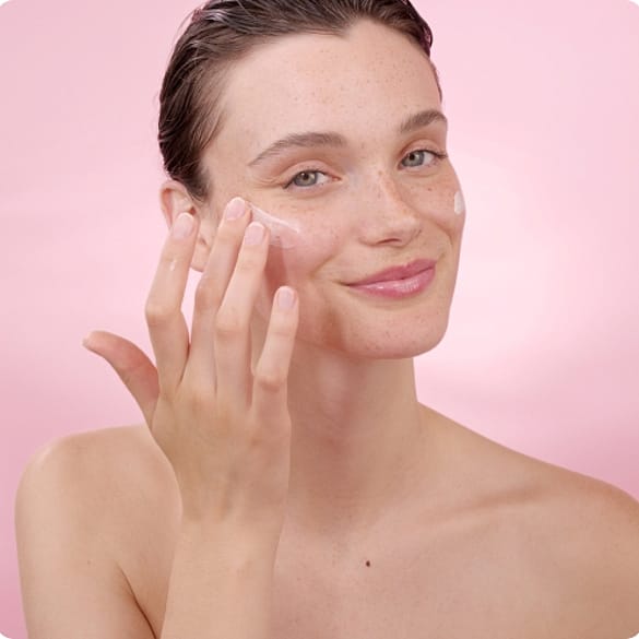 Une jeune femme applique le soin de jour lissant Weleda sur sa peau