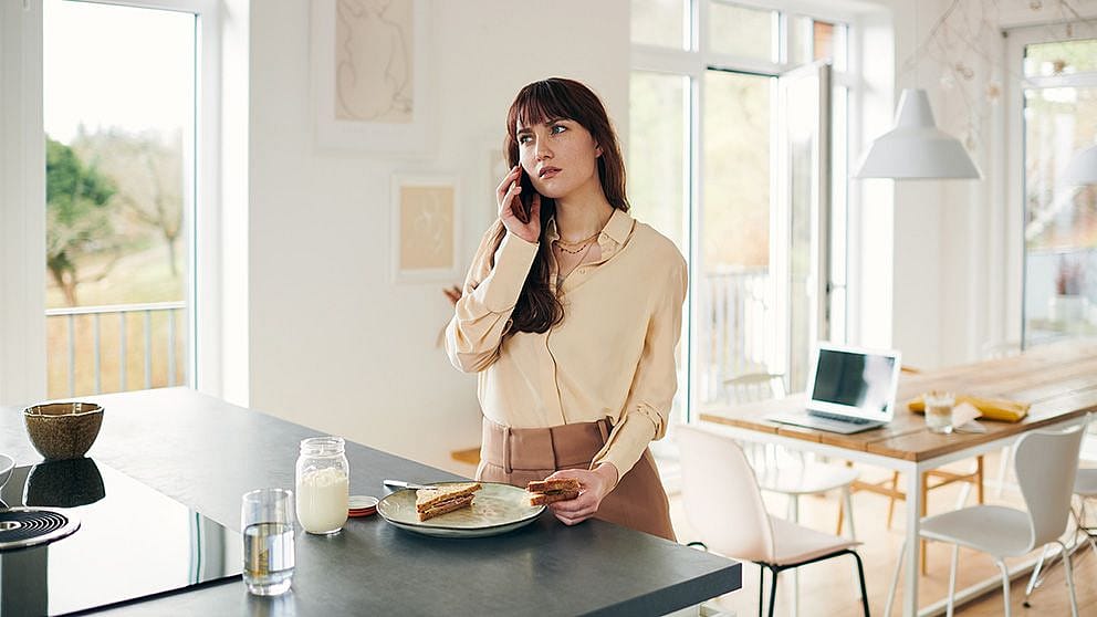 Femme debout en train de manger et de téléphoner