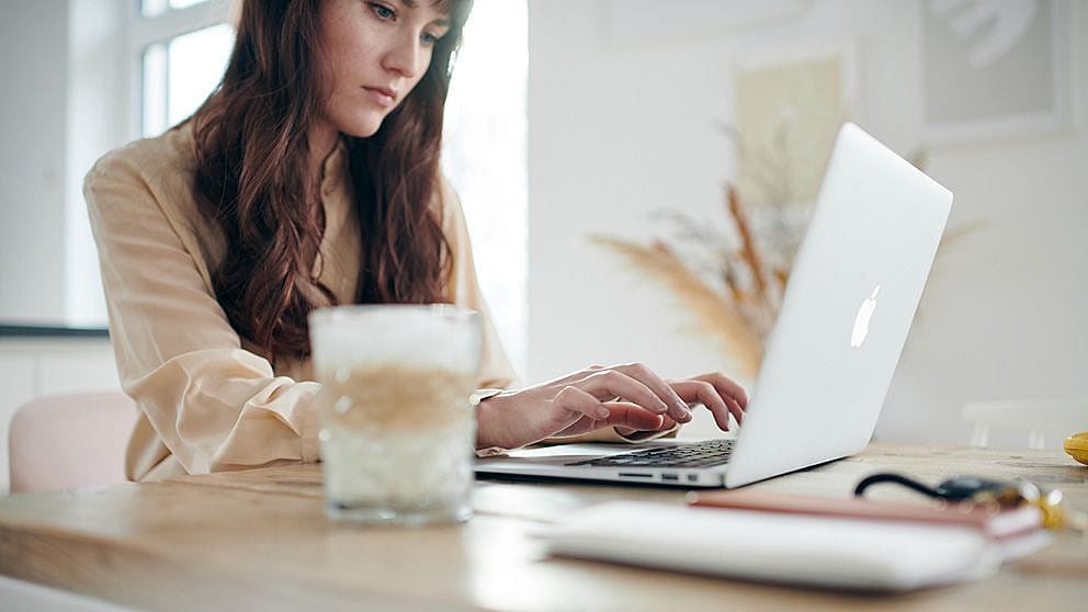 Une femme écrit sur son ordinateur portable