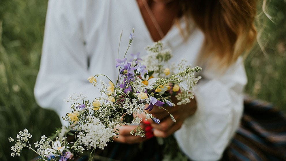 Couronne de fleurs dans les mains d'une jeune femme en chemise blanche