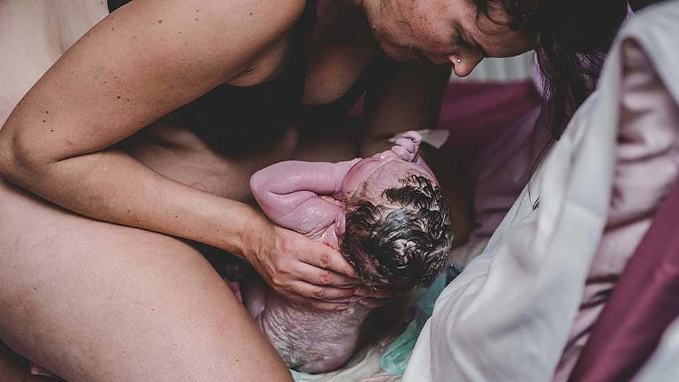 Une femme accueille l'enfant à la naissance