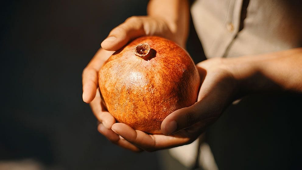 Une femme tient une pomme grenade dans ses mains