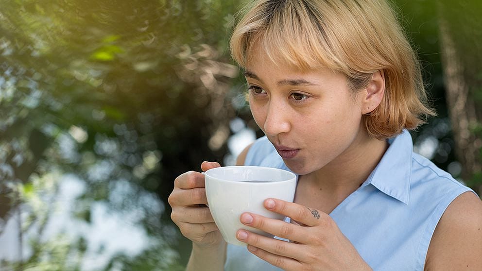La femme boit du thé dans le jardin