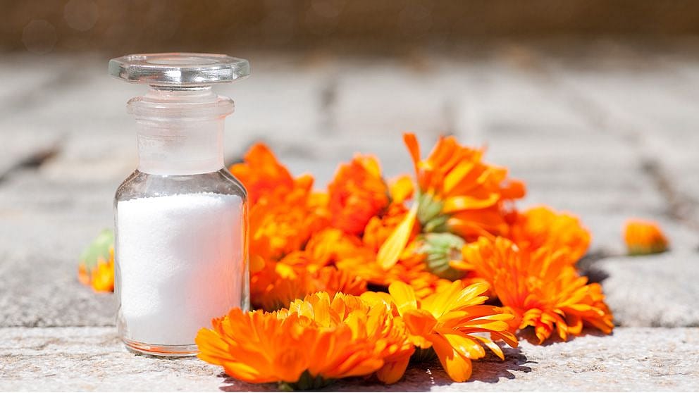 Bouteille de granulés blancs entourée de fleurs de calendula