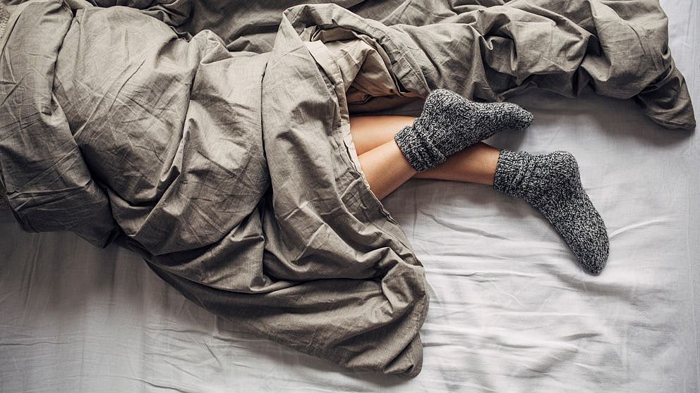 Frau im Bett mit Wollsocken